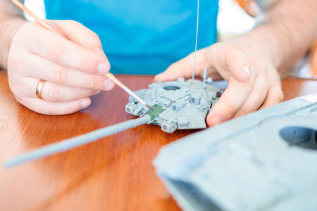 a man assembles a plastic tank model toy, tints the tank turret greenの写真素材