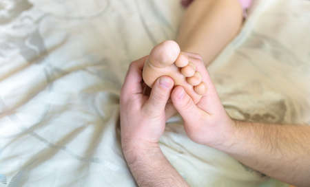 a man doing a foot massage to his wifeの写真素材