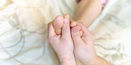 a man doing a foot massage to his wifeの写真素材