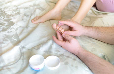 a man doing a foot massage to his wifeの写真素材