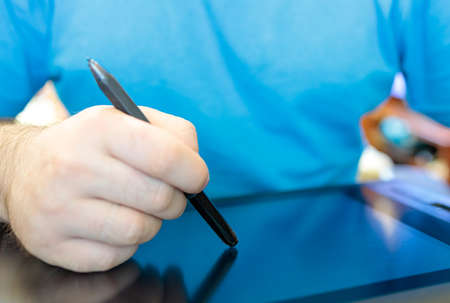 a man erases a drawing with a stylus to draw on a tabletの写真素材