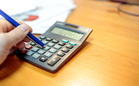 a person counts on a calculator, uses a pen to press buttons