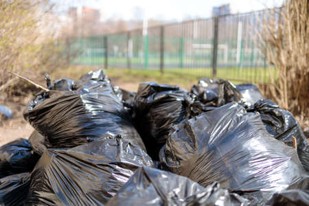 Black bags full filled with autumn leaves in a city street.