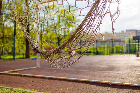 torn soccer net close-up on the background of a soccer fieldの写真素材