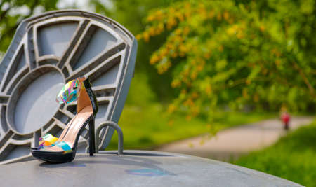 women's shoes with long heels stand on trash can, it is summerの写真素材