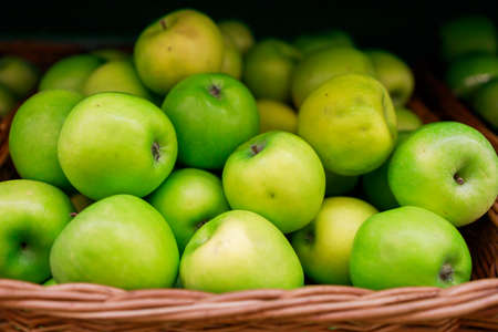 juicy green apples lie in a basket on the counter of the storeの写真素材