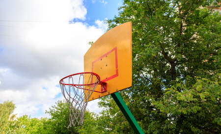 basketball hoop against blue sky and green treesの写真素材