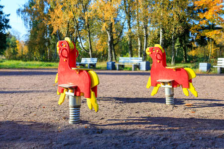 swings in the form of horses in red on the background of benches