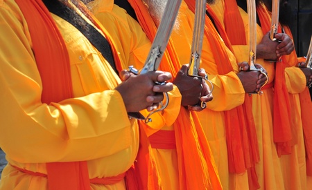 Indian monks in ceremonial orange dress brandishin swordの写真素材