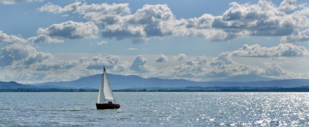Sailing boat on the lake with clouded blue skyの写真素材