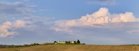 Panoramic view of a farmhouse in the countryside surrounded by vineyards cloudy sky