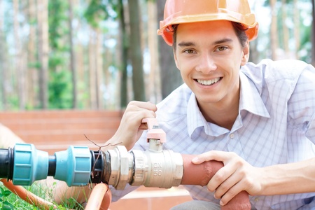 Smiling young worker repairing a pipe outdoors