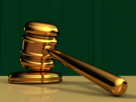 Close Up of a Golden Gavel on a table top with a green curtain backgroundの写真素材