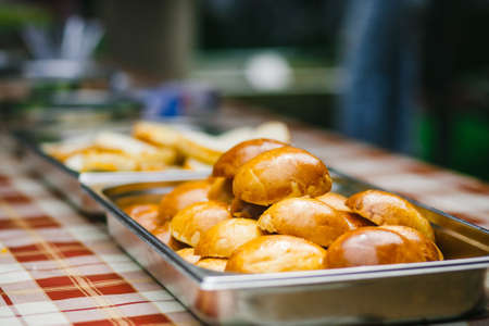 Close up of fresh baked buns in a metal tray on a tableの写真素材