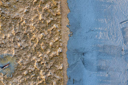 Background texture of a cracked grunge cement wall divided vertically into a gray-blue and beige part with a rough dotted surfaceの写真素材