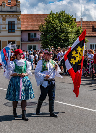Straznice, Czech Republic - June 25, 2022 International Folklore Festival. A boy and a girl carry a flag in a costumed processionのeditorial素材