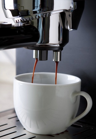 Espresso coffee maker in action with white cupの写真素材