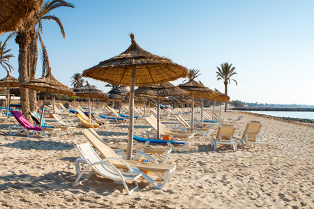 Sandy beach with deckchairs and parasols at sunset
