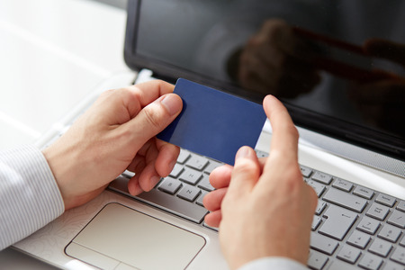 Male hands holding credit card when paying on your notebookの写真素材