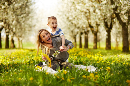 Mother playing with her son in a blossoming orchardの写真素材
