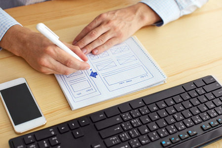 Man sketching on paper webdesign behind the desk
