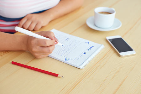 Woman sketching on paper webdesign behind the desk