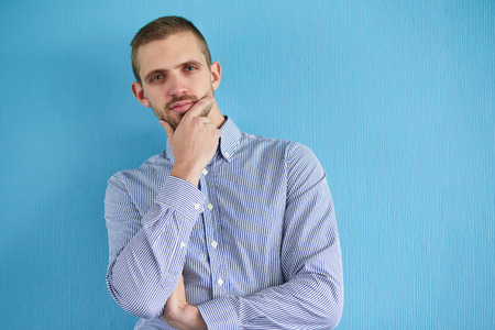 Pensive man leaning against a blue wall