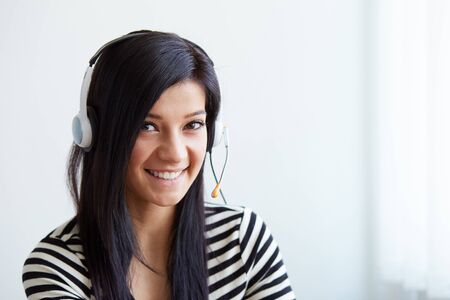 Happy female customer support phone operator at workplaceの写真素材