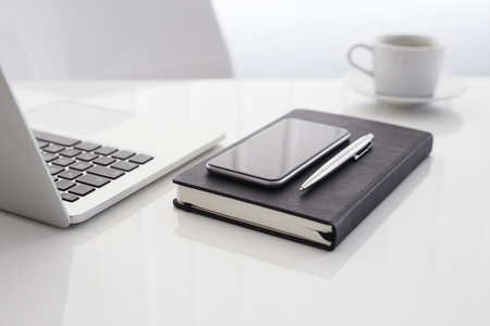 Workplace with open laptop, diary, mobile phone and coffeeの写真素材