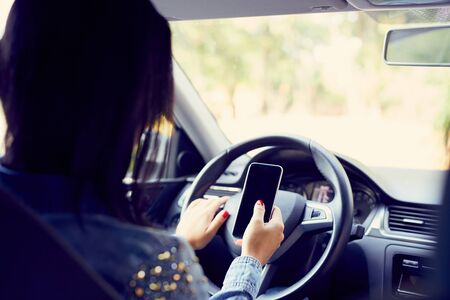 Woman in the car holding black mobile phone
