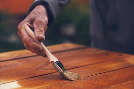 Female hand with paintbrush painting on a wooden tableの写真素材