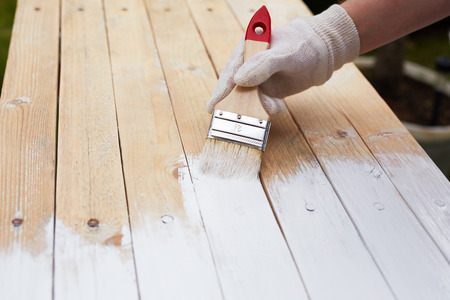 Man hand with paintbrush painting on a wooden tableの写真素材