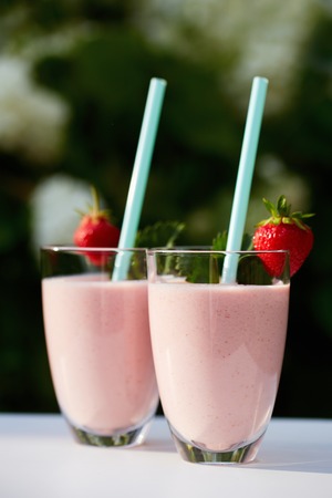 Glasses of fresh smoothie with strawberry on white tableの写真素材