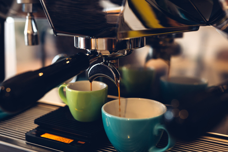 Coffee machine pouring coffee into a two colored cups, toned imageの写真素材