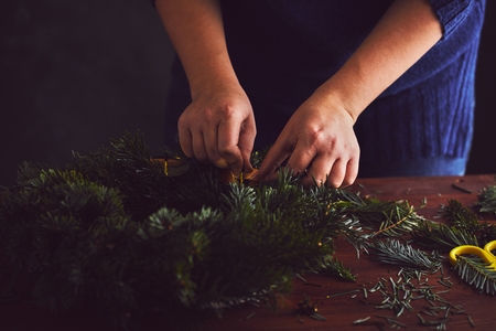 Woman attaches candle holder on a Christmas wreathの写真素材