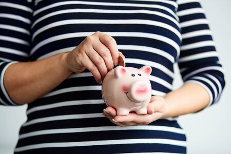Pregnant woman saves money in piggy bank in the office