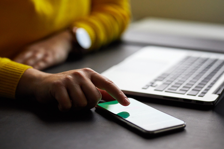 Female hands with mobile phone and laptop in the officeの写真素材