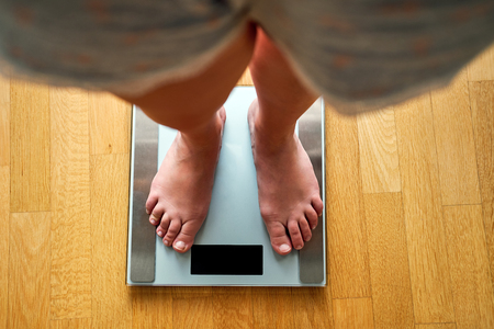 Female bare feet with weight scale, top view