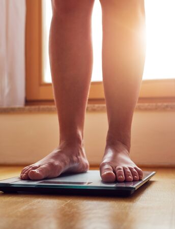 Female bare feet on weight scale at sunshineの写真素材