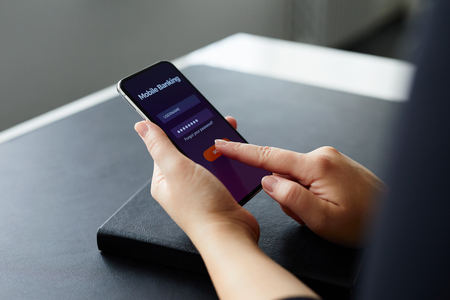 Woman signs up for banking with their mobile phone in the officeの写真素材