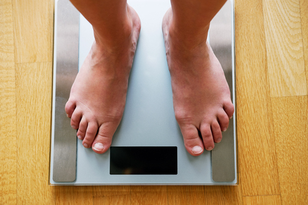 Female bare feet with weight scale, top viewの写真素材