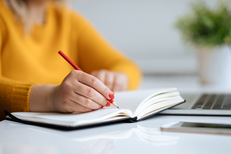 Woman writes notes on a diary in the officeの写真素材