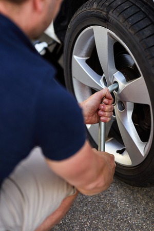 Man changing car tire with wheel wrench, close up