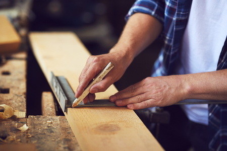 A carpenter uses a framing square in a carpentry shop.の写真素材