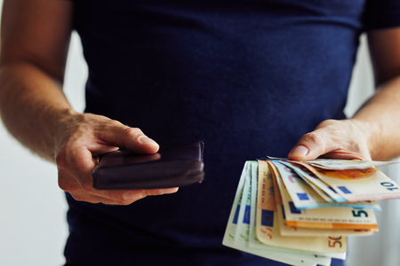 The man with euro banknotes and brown wallet in the office