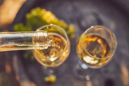 Pouring white wine into glasses, top view.の写真素材