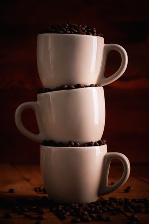 Three cup full of coffee beans on a wooden tableの写真素材