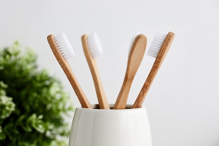 Close up of four bamboo toothbrushes in gray glass