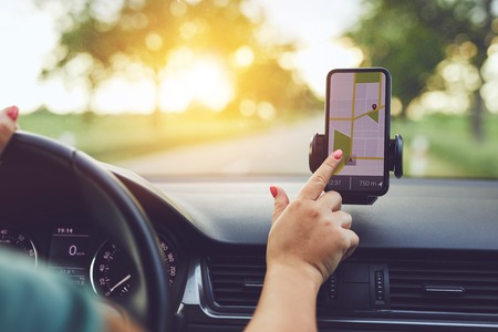 Close-up of woman using GPS navigation in mobile phone while driving car at sunset