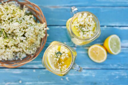 Top view of two glasses of elderflower lemonade with basket of elderberry flowersの写真素材